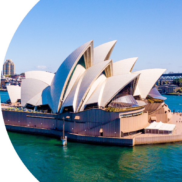 The Sydney Opera House, with its famous sail-like architecture, set against a clear blue sky and the surrounding harbor.