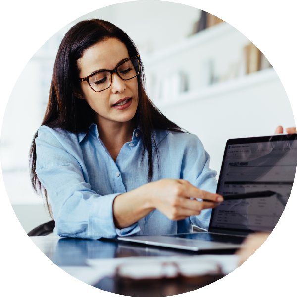 A woman wearing glasses pointing to a computer screen
