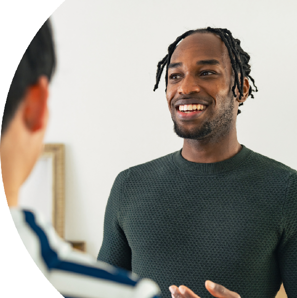 A man smiling and talking during a conversation with another person.
